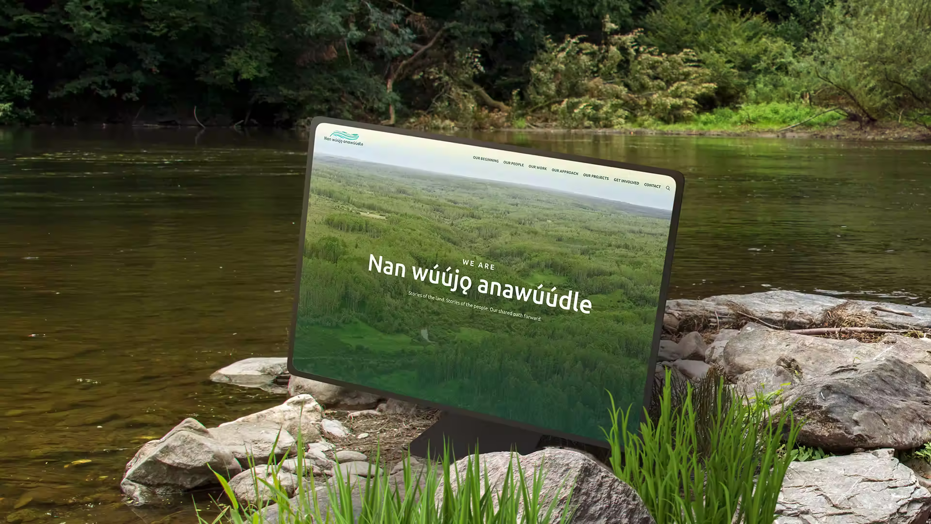 A computer screen displays a website with the text "WE ARE Nan wúújq anawúúdle" and "Stories of the land. Stories of the people. Our shared path forward.